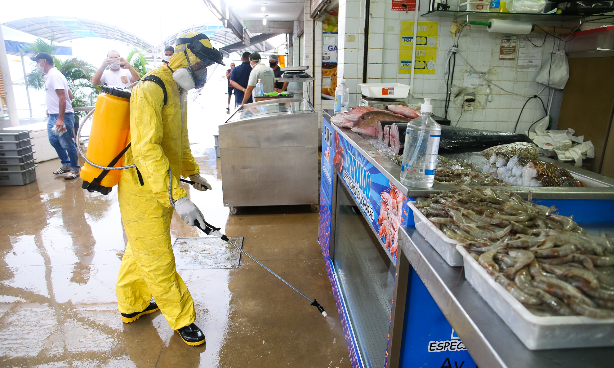 homem manuseia um equipamento que solta jato higienizador em um quiosque do mercado dos peixes